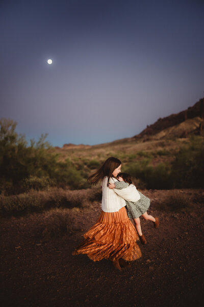 woman and daughter embraced in arms  on the rocky coast of hawaii