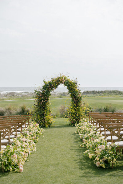 indian groom wearing a black tux and dried floral boutonniere wraps arm around the bride at the brown hotel in louisville in front of a baby breath ceremony arch with pastel flower colors by louisville wedding florist roots floral design