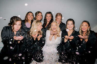 bride and bridesmaids blow confettie