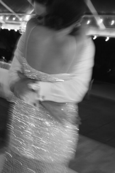 Film photo of bride walking away from camera while groom holds the end of her veil