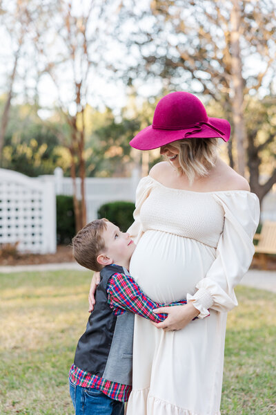 boy hugging mom's baby bump at Cypress Gardens