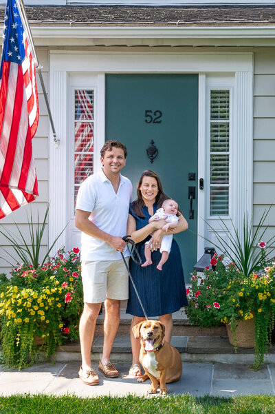 Family with newborn baby posing by their front door.