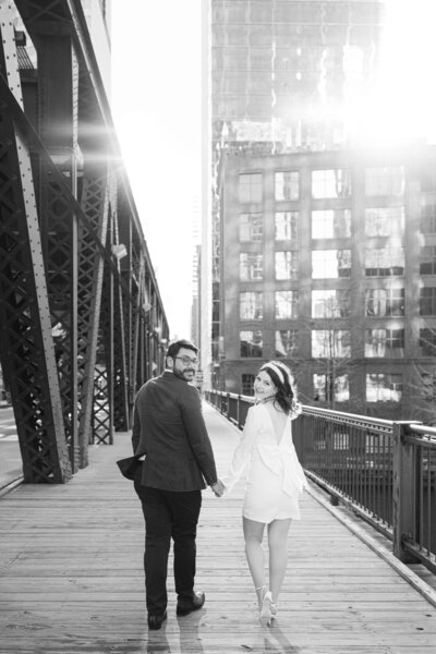 Downtown Chicago engagement photos; a man and woman walking across one of Chicago's many drawbridges