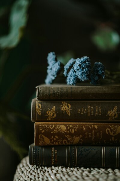 Stack of books with flowers resting on top, symbolizing Lumina Literary Tours for women who love reading and travel.