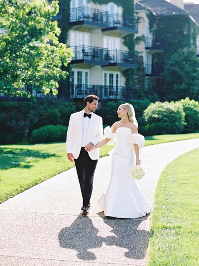 Bride and groom walking together as they hold hands for their wedding portraits.