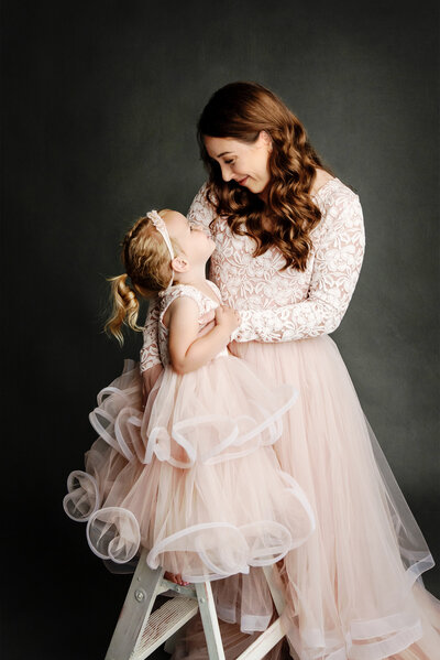 Mom and daughter looking at each other smiling posing for the camera