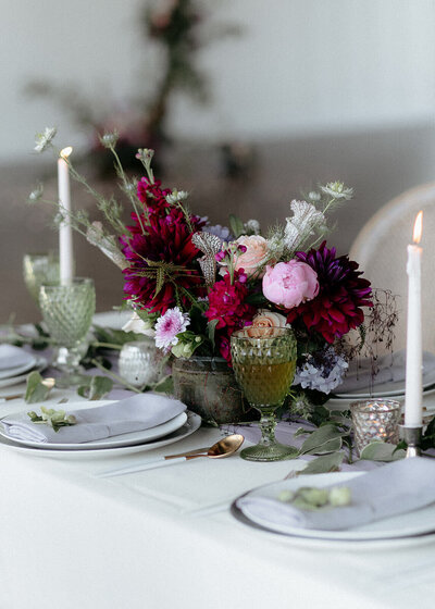 Wedding reception table decorated with flowers, candles, and glassware.