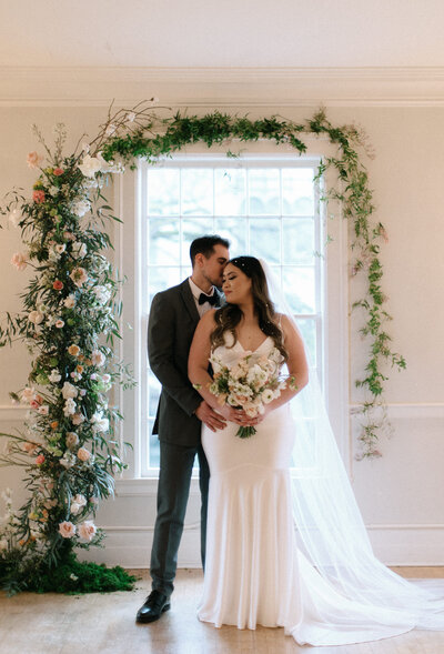Groom embraces his bride who holds her wedding bouquet