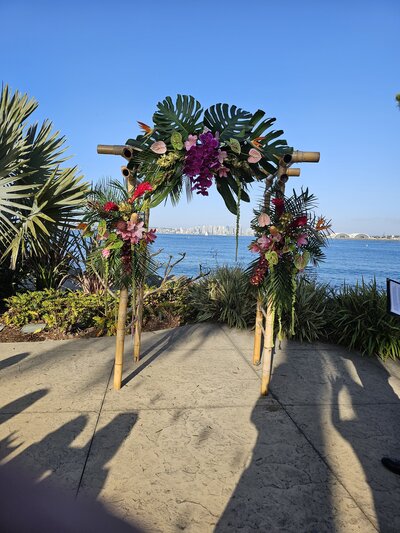 tropical floral arch at outdoor wedding on San Diego coastline