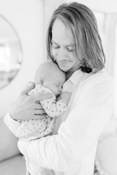 Black and white image of father smiling down at his baby daughter