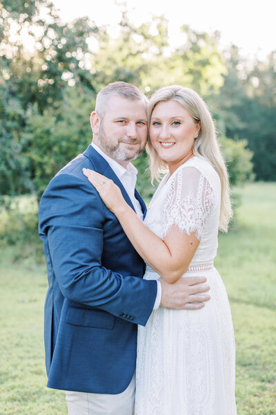 A couple holds onto each other while smiling at the camera.