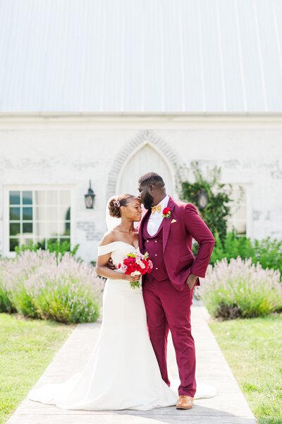 Groom kissing bride on her forehead in front of lavender