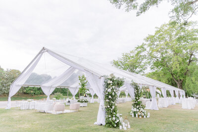 A monochrome image of an elegant bride and groom during their first dance as he wears a full traditional tuxedo and her diamond earrings sparkle in the light from the lanterns overhead.