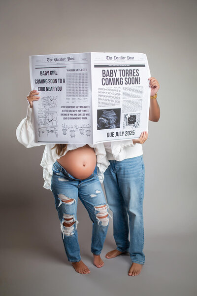 Creative and fun studio maternity session of woman and man holding newspaper announcing newborn arrival