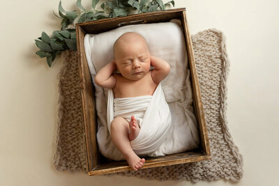 Posed newborn boy with his hands behind his head