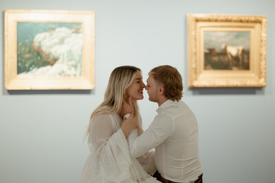 couple soft kissing inside art gallery photoshoot