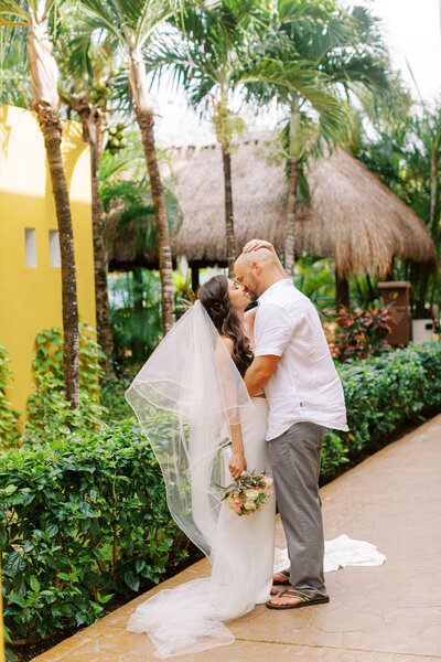 couple kissing in front of palm trees 