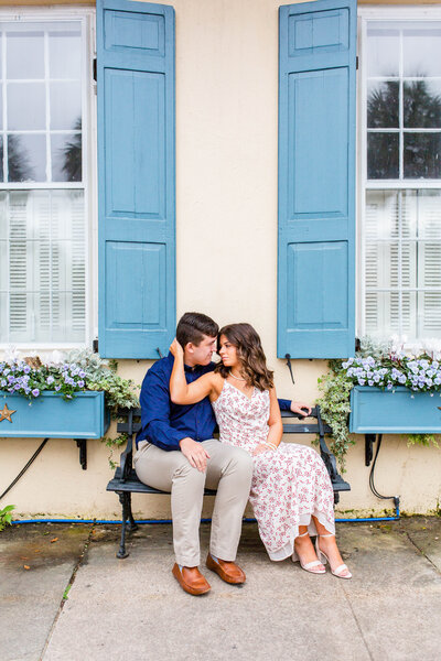 couple on bench in front of pastel home in Charleston.