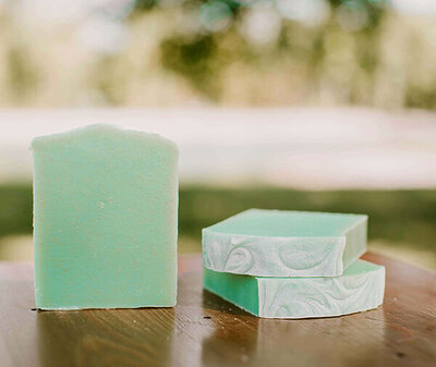 coconut lime verbena scented bars of goat milk soap displayed on a table