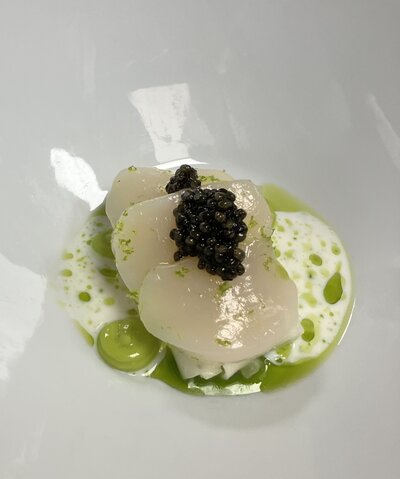 Exquisitely plated gourmet dish featuring scallops and Caviar, elegantly paired with a fine wine, served at a CuisineMusique event.