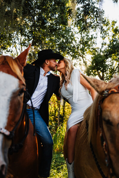 Shannon Lee, a Florida elopement photographer capturing a couple sharing a kiss on horseback, surrounded by a beautiful forest backdrop.