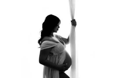 Atlanta, Georgia maternity photographer, Maternity and Newborn Studio of Atlanta by Casey McMinn Photography with 35 week pregnancy portrait of woman wearing white sheer gown holding baby bump.