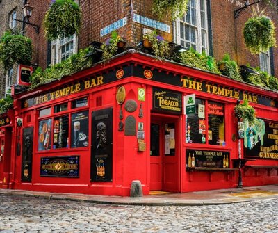 The iconic Temple Bar in Dublin, Ireland, with its vibrant red facade adorned with gold lettering, hanging flower baskets, and vintage signage. Nestled on a cobblestone street, this lively pub represents the cultural and social experiences that vacation fundraising can help make accessible to travelers.