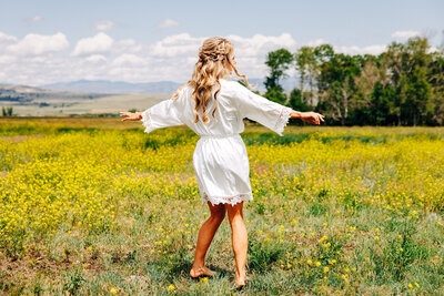 Bride twirling in field in white robe at Staubach Creek Ranch in Winston, MT