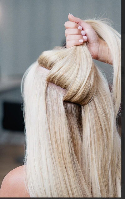 Headshot of certified hair stylist with blond hair extensions smiling wearing black