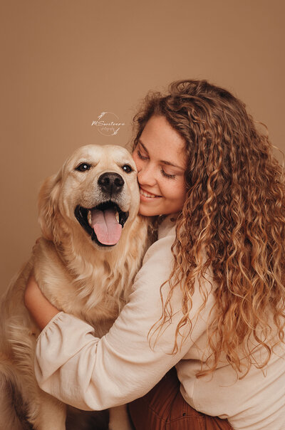 Dogmom met haar golden retriever al knuffelend voor achtergrondpapier in een fotostudio te Geel
