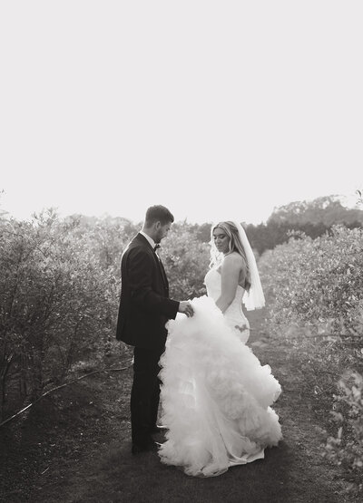 photograph of couple groom holding bride dress while walking