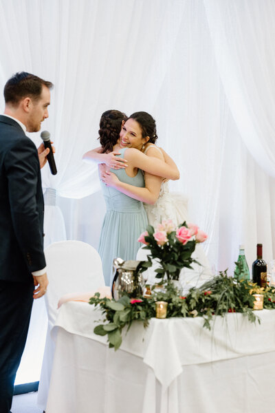 The bride's daughter hugging her mom as she gives her congratulations to the couple