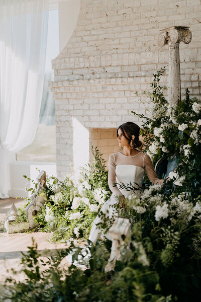 Bride surrounded by lush wedding floral installation