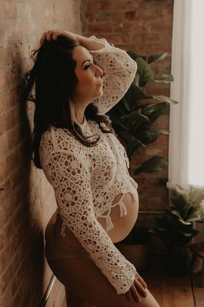 Pregnant woman standing against a brick wall in Canandaigua, NY
