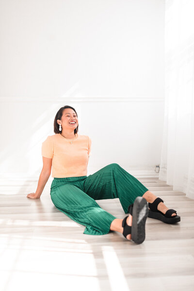 woman sitting on the floor leaning back on her arms while smiling