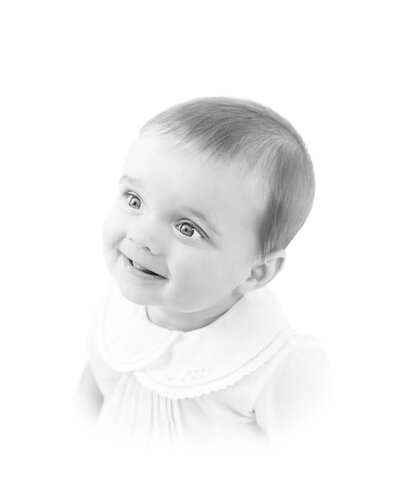 Classic heirloom portrait of a young child with a soft smile, dressed in a traditional outfit with delicate pleats. This timeless and artistic children’s portrait reflects the refined and elegant style of a Birmingham portrait photographe