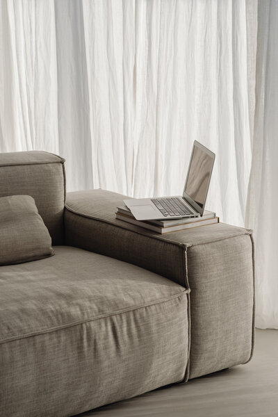 Couch with a laptop sitting on the arm of the couch