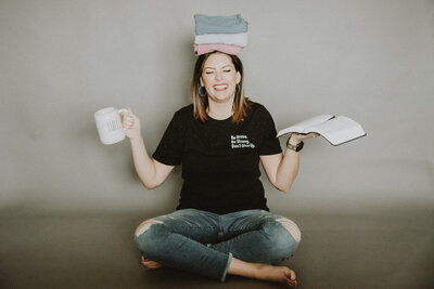 woman holding coffee cup, notebook, and t-shirts