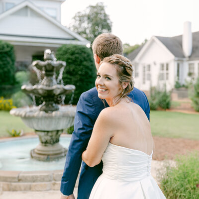 Virginia Wedding Photography of a  bride hugging a groom from behind , looking back and smiling
