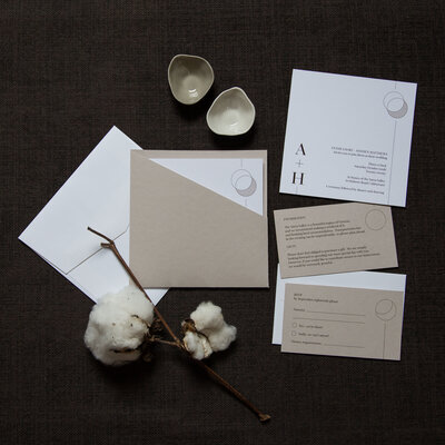White and natural stone wedding invitation with a pocket and circular moon graphic