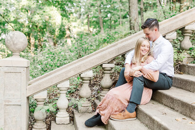 a man sitting with his arms around his fiance while sitting on stone steps