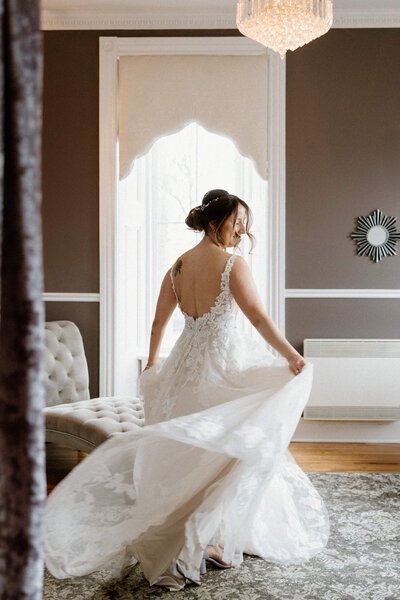 Back view photo of a bride spinning around while holding her wedding dress at the hotel