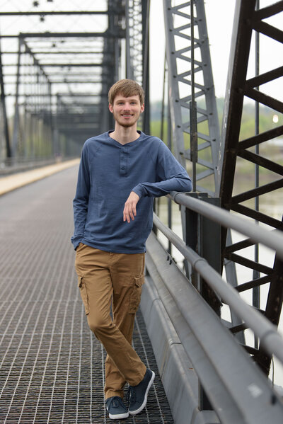 Senior photos of a guy in downtown Harrisburg, PA standing on a metal bridge