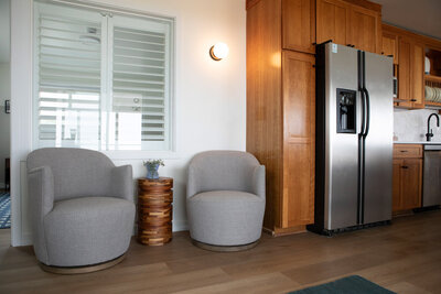 Seating lounge in Oregon Beach house rental featuring two gray chairs and a wooden side table below a window.
