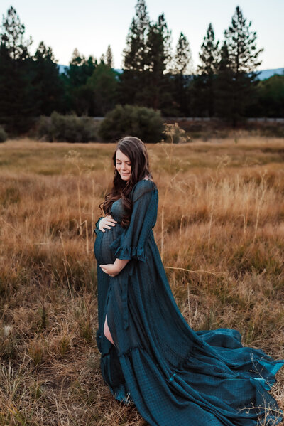 Expecting mother wearing a long flowy navy gown in Crystal Peak Park.