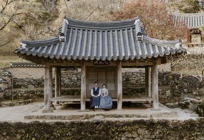 couple sitting on a hanok dressed in hanbok in south korea