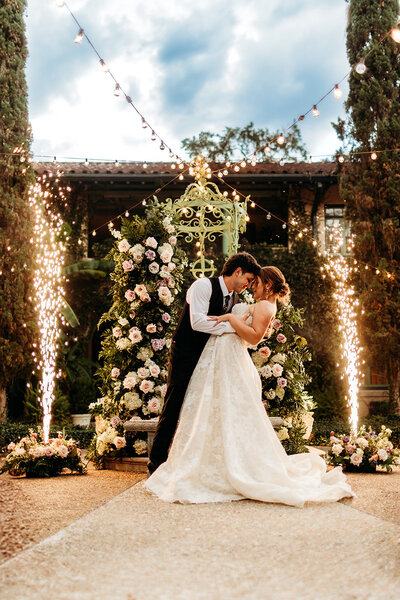 Bride and groom posing in front of a flower arch during a Jacksonville, Florida wedding.