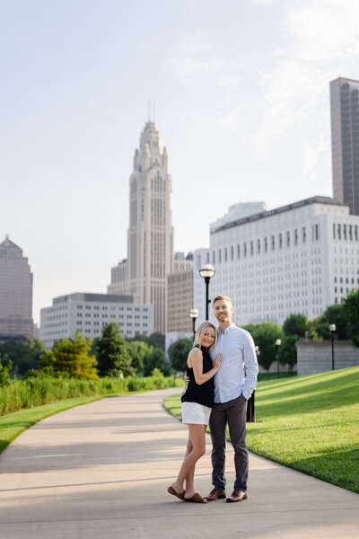 A couple hug each other and smile during their downtown Columbus engagement shoot