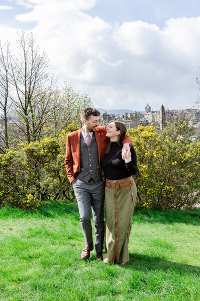 bride and groom walk arm in arm on a hill top