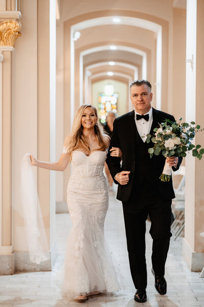 bride and groom walk through arches